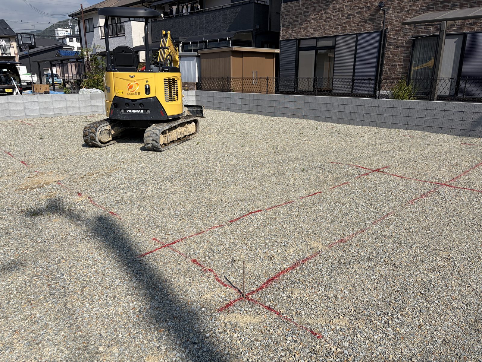 地縄が引かれた住宅基礎工事現場と重機の写真